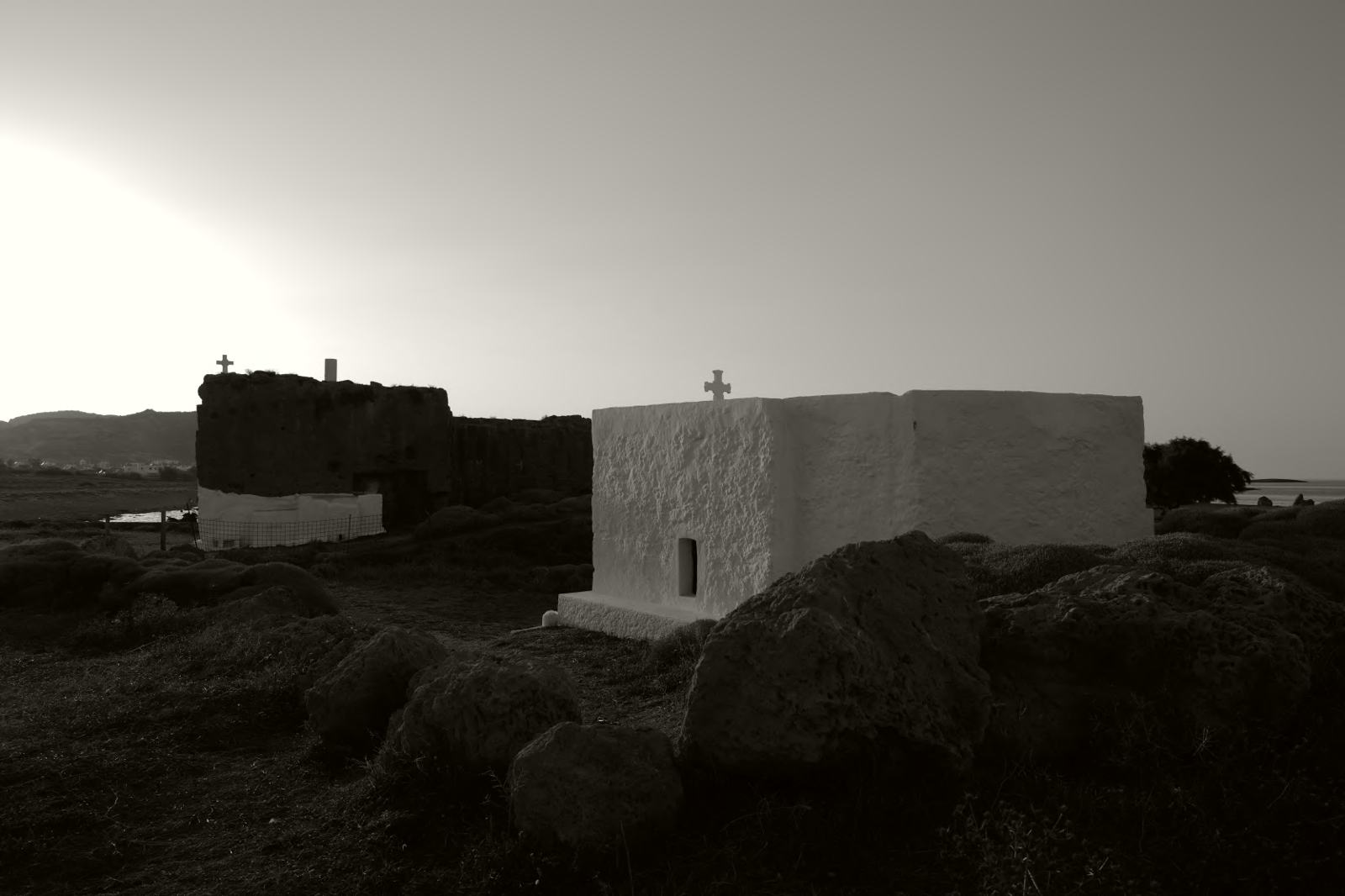 A white chapel in silhouette beside a dark rock at sunset